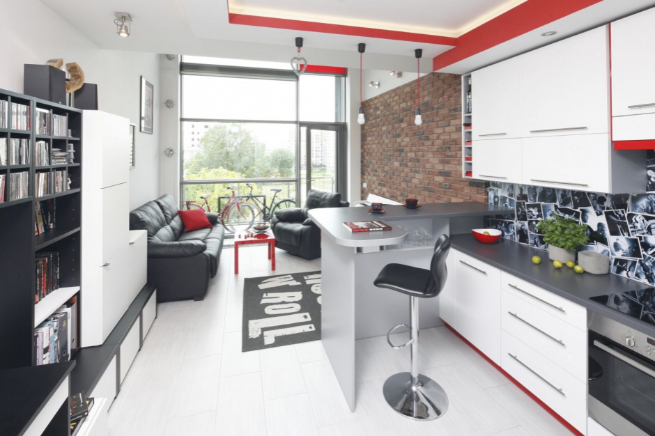 Nad blatem półwyspu, wzdłuż symbolicznej granicy kuchni z salonem zawisły trzy żarówki na odsłoniętych oplotach. Idealnie harmonizują ze stylistyką loft oraz wpisują się kolorystką w wystrój wnętrza. Projekt: Monika Olejnik. Fot. Bartosz Jarosz. Modna kawalerka w stylu loftowym