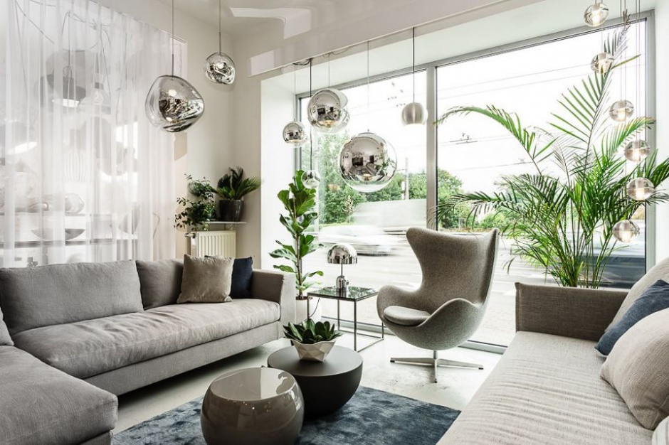 Liczne podwieszane srebrzyste kule i formy kulo-podobne stanowią oświetlenie w tym eleganckim szarym salonie. Fot. Mesmetric Concept Store Jak nalepiej oświetlić salon?