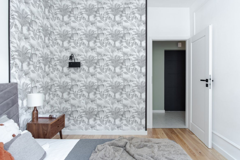 Kolor łóżka idealnie uzupełnia tapeta w botaniczne wzory. Fot. Bernadetta Kuczyńska Interior Photography Światło i klimatyczna cegła. Zobacz eleganckie mieszkanie projektu Latre Design