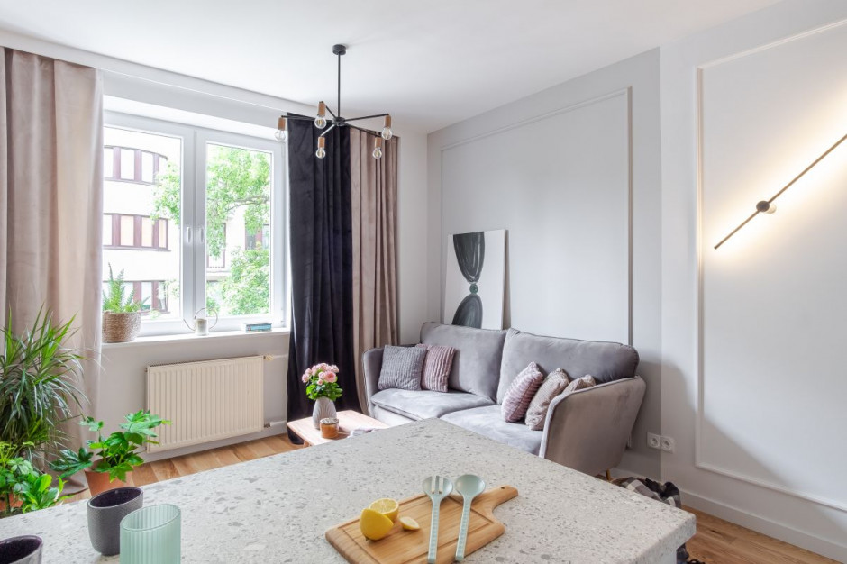 Białe ściany to idealne tło dla szarej sofy. Fot. Bernadetta Kuczyńska Interior Photography Światło i klimatyczna cegła. Zobacz eleganckie mieszkanie projektu Latre Design